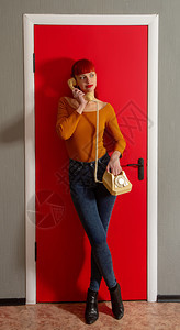 美女在旧拨号电话上说在明红门的背景上使用扭曲的铁丝图片