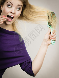 快乐的女士用刷子梳她的头发年轻微笑着女与天然金发直长头工作室拍摄在灰色上妇女用刷子她的长头发图片