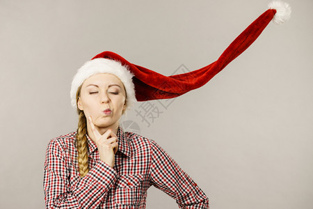 年轻女人有趣的少闭着眼睛戴吹圣达克莱斯帽子圣诞时光工作室拍摄在灰色上有趣的女孩背景图片