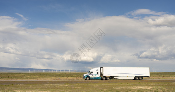 在犹他州公路上挂有货运集装箱的白色大卡车背景图片