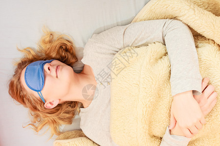 睡在床上的疲劳妇女戴蒙眼睛的睡面具年轻女孩睡午觉着妇女戴蒙眼睛的睡面具图片