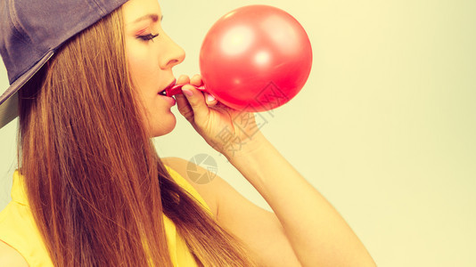 年轻潮流女子准备生日庆典装饰女青少年戴帽子发红气球女青少年充气红球图片