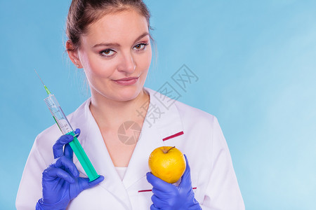 配有苹果和注射器的科学家医生持有转基因水果的妇女化学家转基因食品改制使用苹果和注射器的科学家医生转基因食品带苹果和注射器的科学家图片