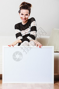 广告概念时尚女坐在沙发上用空白的演示板展横幅标志的女模型在广告牌上签名复制文本空间图片