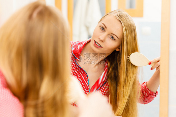 女人在浴室梳她的长发看着镜子女孩在照顾下刷新发型理概念女人在浴室刷她的长发图片