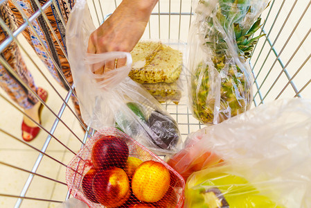 在超市自助服务杂货店装购物车的女顾客里面有水果和蔬菜零售在超市装杂货的购物车图片