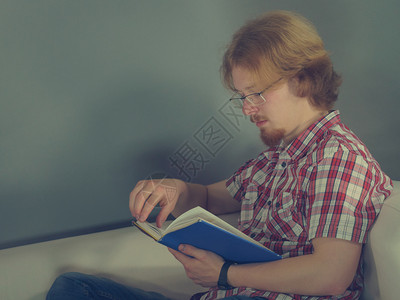 一个人在沙发上看有趣的书享受休闲时间放松概念男人在沙发上放松阅读书图片