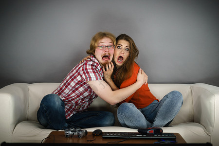 坐在沙发上看恐怖电影的有趣情侣害怕被拥抱图片