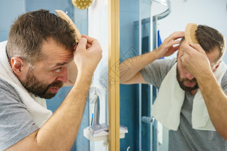 成人男子站在浴室镜前用梳短头发图片