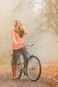 开心女子在起雾的森林公园骑着自行车图片