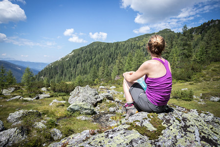 徒步旅行的体育女运动员坐在一块石头上享受着山地的景色图片