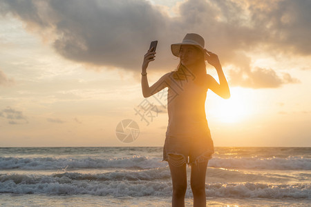 快乐的亚洲女在海滩社交媒体上自拍图片