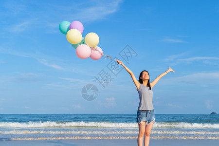 天空气球快乐的亚洲女在泰国普吉中午的海洋或自然度假室外旅行中在海滩上携带多彩气球背景