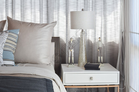 时髦的卧室内设计床边有带条纹的枕头和装饰桌灯图片