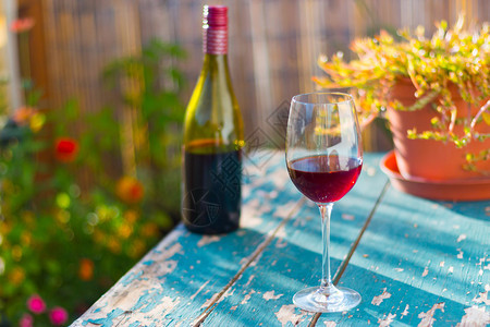 红酒杯放在老旧的木制桌子上在晚的阳光下在自己的花园里享受它图片