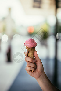 女人手里握着草莓冰淇淋阳光明媚的夏日模糊背景图片