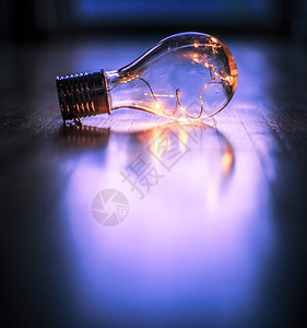 LED灯泡躺在木制地板上是思想和创新的标志是模糊背景中的窗口和灯光图片