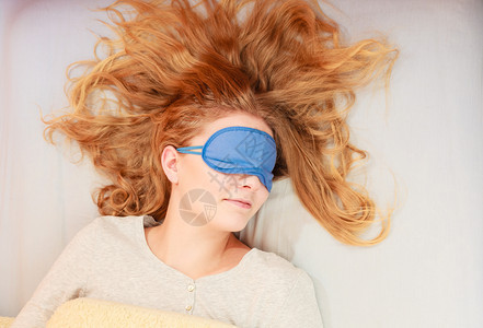 睡在床上的疲劳妇女戴蒙眼睛的睡面具年轻女孩睡午觉着妇女戴蒙眼睛的睡面具图片