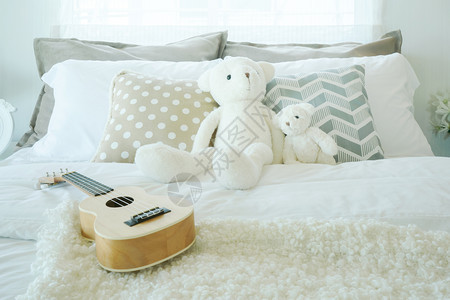 Ukulele和Teddy熊在儿童卧室的床上图片