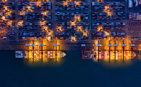 集装箱货运船在城市进出口业务和物流国际货进出口业务中的空最高视野夜间由起重机在香港维多利亚向口运输背景图片