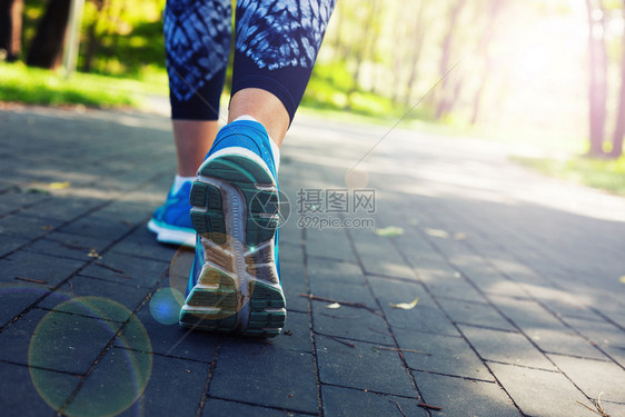 在城市公园路上跑的女青年运动员跑腿图片