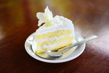白面蛋糕切片和木桌背景花美味椰子蛋糕和勺图片