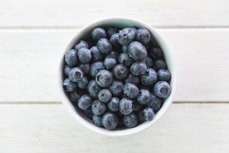 蓝莓水果在木桌背景的碗里图片