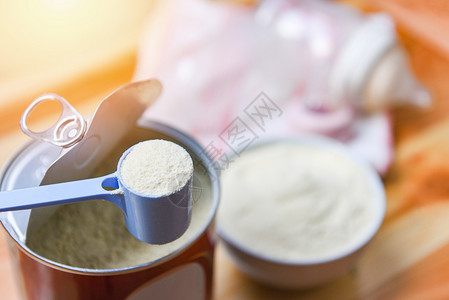 用勺子加罐头的奶粉和木桌背景的婴儿瓶装奶粉背景图片