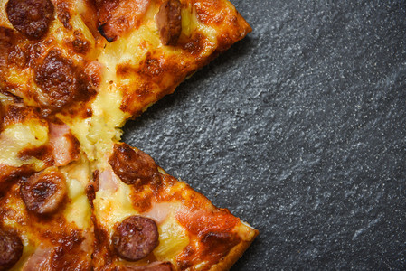 黑盘上的披萨切片美味的快餐意大利传统披萨奶酪与Mozzarella熏猪肉香肠菠萝火腿酱图片