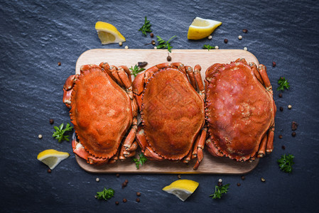 木板上用柠檬在盘子里的烤螃蟹放在黑板顶视线烤海鲜的石蟹上图片