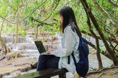 在泰公园旅行和户外度假期间在热带森林瀑布使用笔记本电脑图片