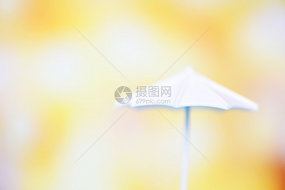 在bokeh和黄色模糊背景上关闭白色雨伞有选择的焦点图片