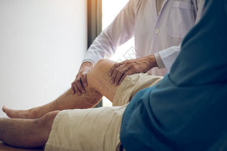 理疗师正在用病人膝盖的手柄检查疼痛情况背景图片