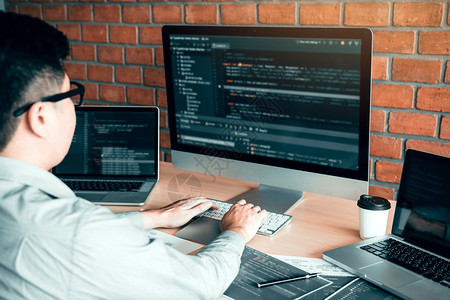 亚洲人工作代码程序开发者计算机网络开发工作设计软件在办公室桌上背景图片