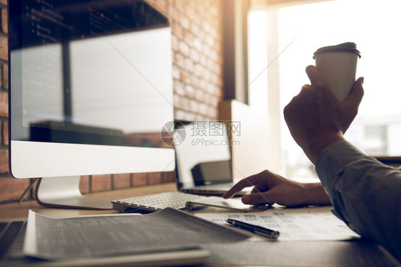 早上和一个在办公室喝咖啡并看电脑屏幕的程序开发者一起工作图片