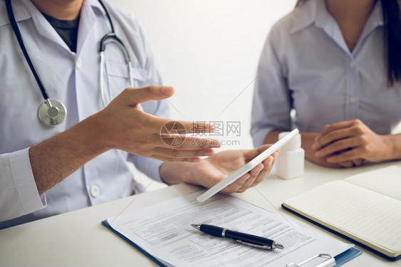 亚洲医生在诊所与病人交谈时使用平板片解释病人状况和治疗结果图片