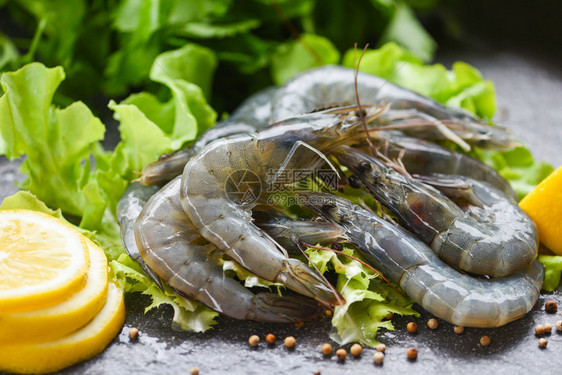 在海产食品餐厅中盘子上生虾新鲜配有香料柠檬和蔬菜沙拉生或深底绿橡树的新鲜虾图片