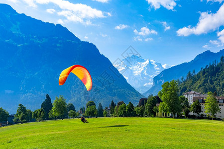 在瑞士伯尔尼高地重要旅游中心因特拉肯市霍赫马特公园降落的滑翔伞本底可见栋佛劳图片