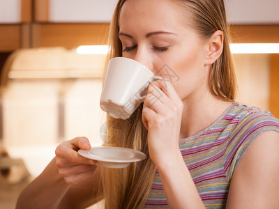 快乐的女士站在厨房喝着咖啡的茶享受她放松的空闲时间快乐的女士喝着咖啡茶图片