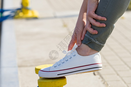 个人调整将鞋带绑在白色运动鞋上将皮绑在黄色圆球针上户外鞋很适合温暖的天气图片