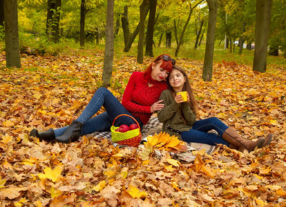 穿着明亮毛衣的年轻母亲和小女儿在大自然野餐上喝茶母亲和女儿野餐图片