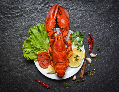 海鲜龙虾盘上龙虾的海鲜壳鱼虾和深底柠檬沙拉生菜蔬和番茄背景