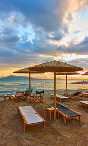 希腊阿埃吉纳岛日落时海边滩带沙长和草伞希腊Aegina岛图片