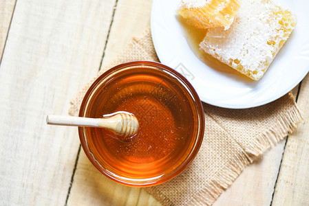 罐里新鲜的甜蜜在木制餐桌背景的白板上有木制甜料和蜂窝图片