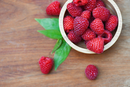 木碗中的新鲜树莓关闭红草莓果和绿叶顶视图图片