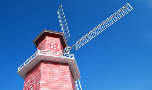 花园中蓝色天空背景的粉红风车力涡轮机高清图片