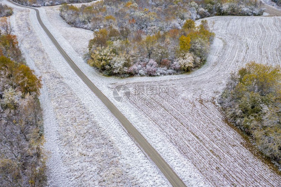 在密苏里西部的蜜溪保护区空中观测到早期积雪粉尘下的石灰路森林和收割的玉米田图片