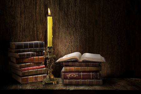 RetroCandelabrara与燃烧蜡烛和木黑背景书籍图片