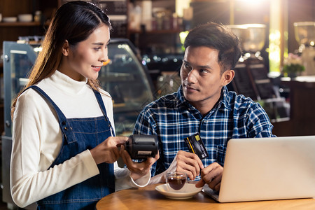 亚洲客户使用无接触nfs技术的信用卡支付咖啡店餐桌服务员购买的费用图片