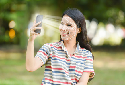 智能手机生物鉴别筛查美丽的妇女微笑并使用移动电话面部识别系统扫描概念背景